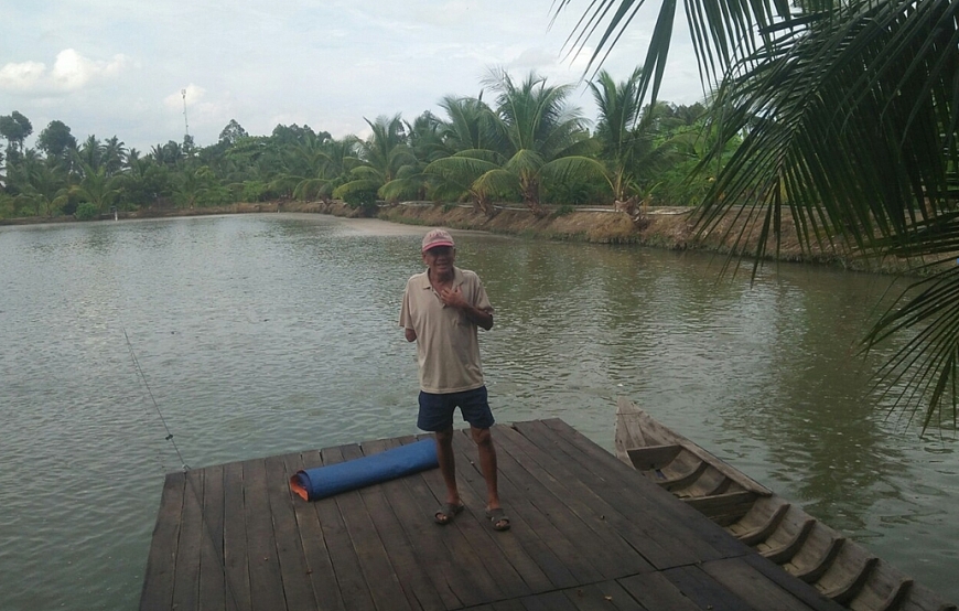 Ông Phan Hòa Nhã và ao nuôi cá tra của gia đình.