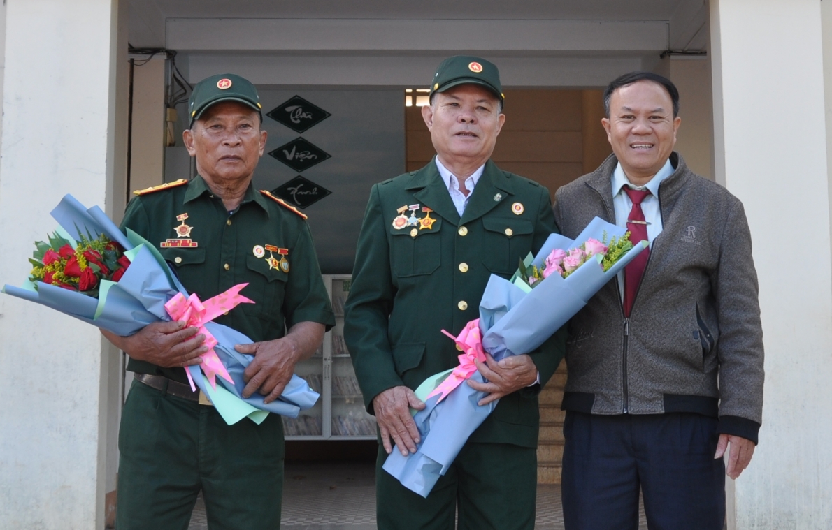 Ông Trần Văn Thu (bên trái) cùng đồng đội được lãnh đạo trường Tiểu học cơ sở Nguyễn Du tặng hoa khi nói chuyện truyền thống với học sinh nhà trường.