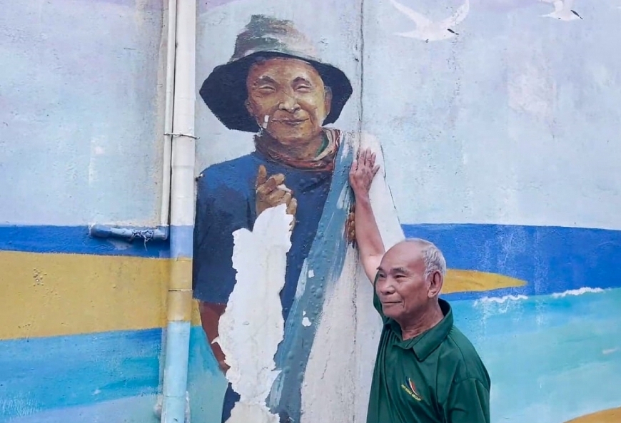 Ông Trước bên bức bích họa chân dung của mình.