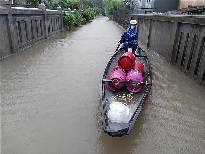 Mưa lớn gây ngập lụt tại Thừa Thiên - Huế, người dân huyện Quảng Điền phải sử dụng ghe để vận chuyển nhu yếu phẩm. Ảnh: Mai Trang/TTXVN 
