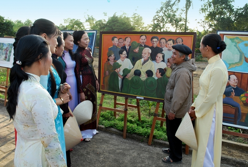 : Cố họa sĩ thuyết trình từng tác phẩm vẽ về Bác Hồ cho các phụ nữ nghe.