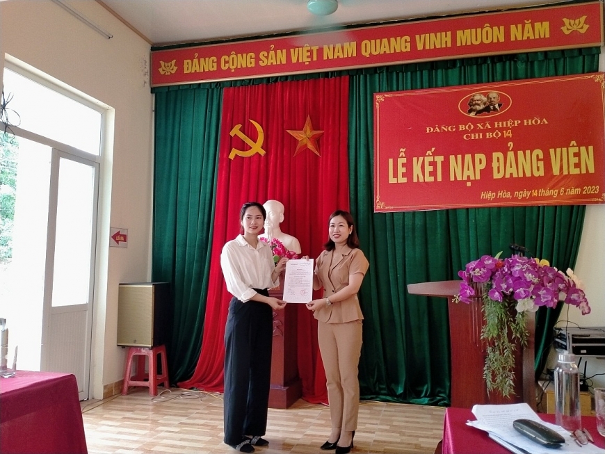  Đồng chí Đào Thị Hương Giang, Bí thư Đảng bộ xã Hiệp Hòa (bên phải) trao quyết định kết nạp đảng viên mới cho đồng chí Vũ Thị Thu Huyền, chi bộ thôn 14 a .