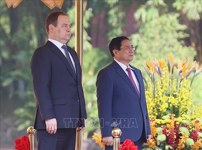 Thủ tướng Phạm Minh Chính và Thủ tướng Cộng hòa Belarus Roman Golovchenko nghe quân nhạc cử Quốc thiều hai nước. Ảnh: Dương Giang/TTXVN