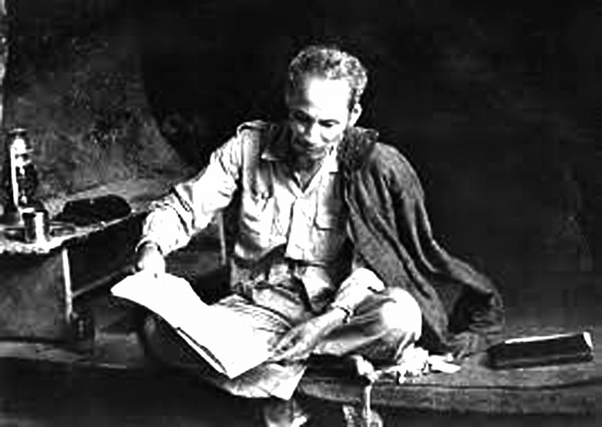 Bác Hồ đọc báo trong hang Pác Bó.