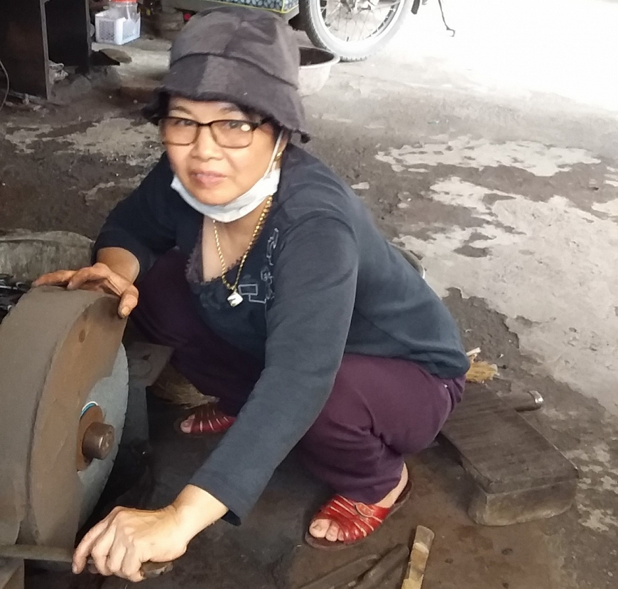 Bà Vui đang sửa máy mài kéo.