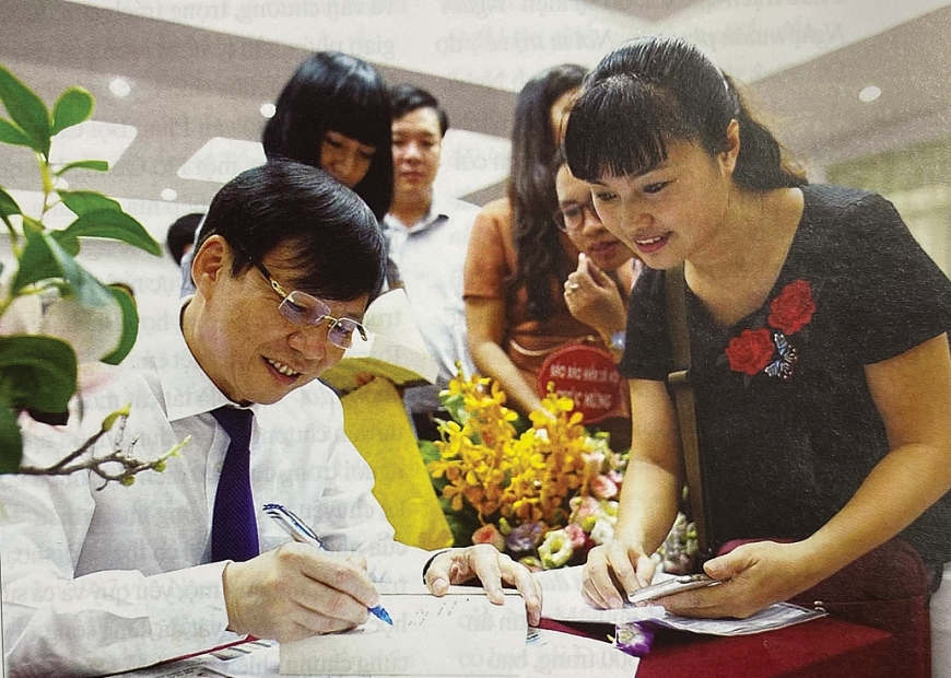 Nhà báo Hồ Quang Lợi kí tặng sách các đồng nghiệp trẻ.