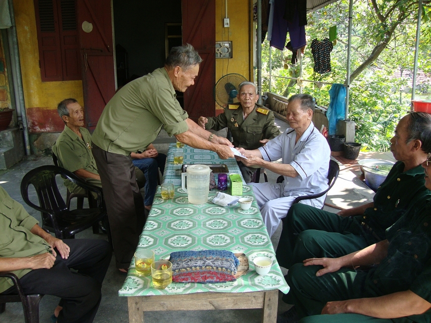 Chi hội trưởng Chi hội CCB Đỗ Đức Hoà (người đứng) trao quà tặng đồng đội ốm đau.