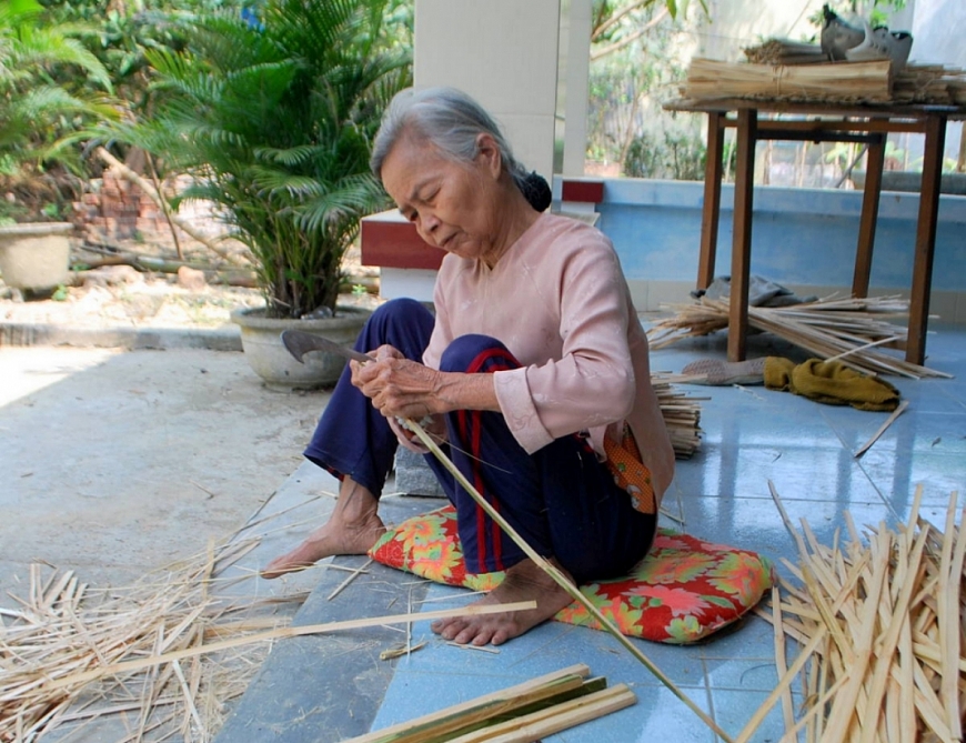 Bà Nguyễn Thị Đích đang chẻ tre đan rổ.