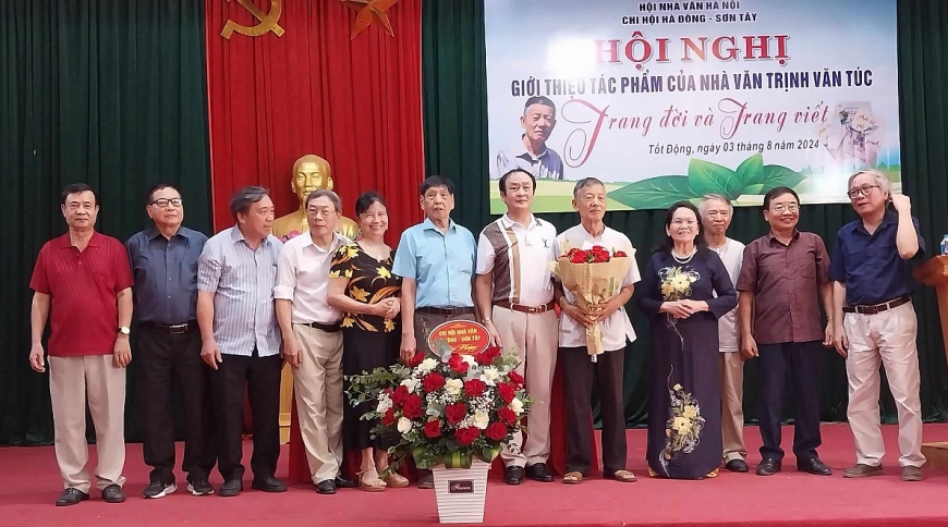 Nhà văn Trịnh Văn Túc (người ôm hoa) nhận những bó hoa tươi thắm do các bạn văn tặng.