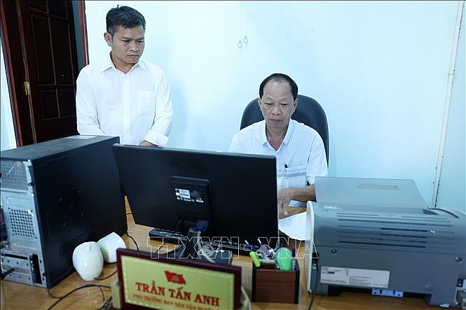 Ông Trần Tấn Anh (ngồi), Phó Trưởng Ban Dân vận Huyện ủy Cư M’Gar, tỉnh Đắk Lắk viết đơn xin nghỉ hưu trước tuổi.
