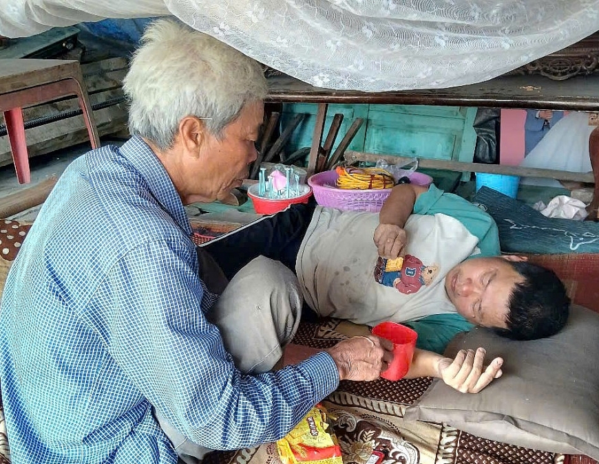   CCB Nguyễn Hữu Nhượng, đang chăm con trai Nguyễn Mạnh Trường, 45 tuổi, thần kinh không bình thường do di chứng chất độc da cam dioxin. 