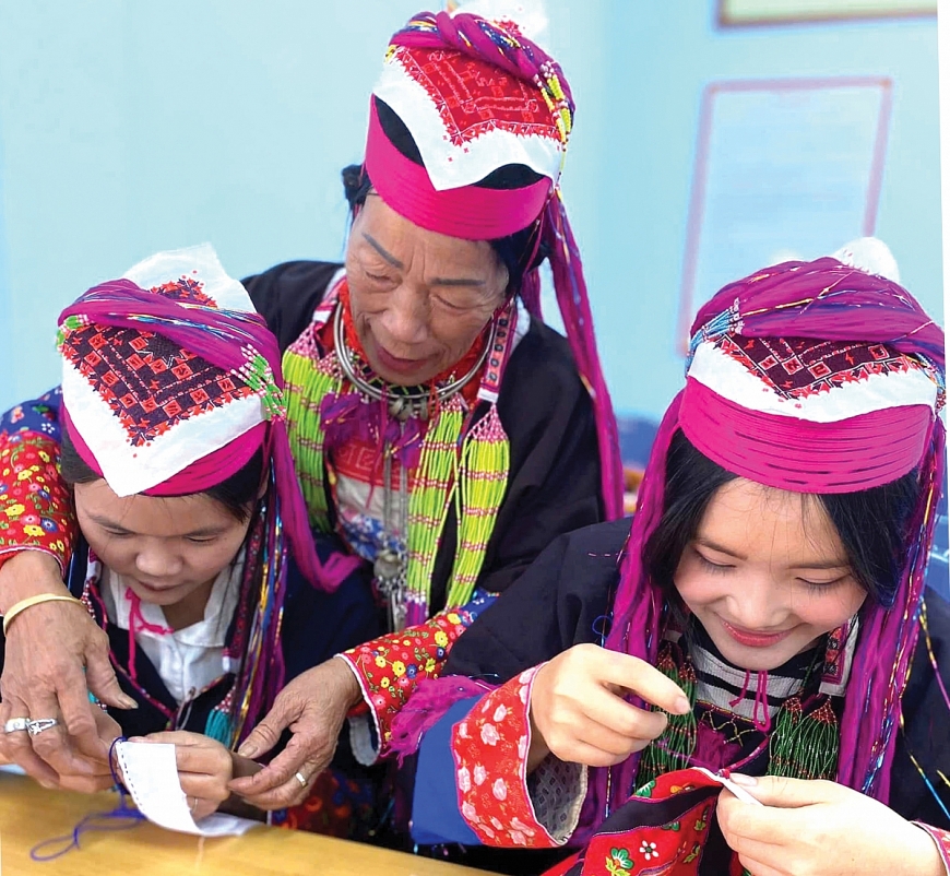 Bà Lý Thị Sáu đang hướng dẫn cho các cháu dân tộc Dao Thanh Y thêu trang phục truyền thống.