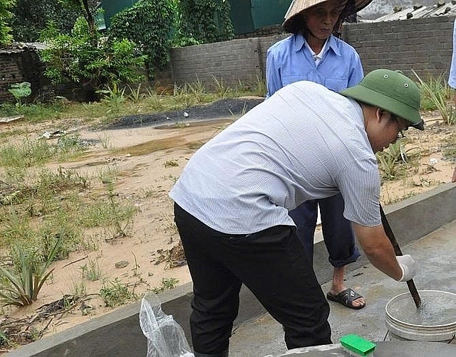 Cán bộ y tế hướng dẫn người dân thực hiện khử trùng bể chứa, khử trùng nguồn nước sạch sử dụng cho sinh hoạt. Ảnh VGPThiện Tâm