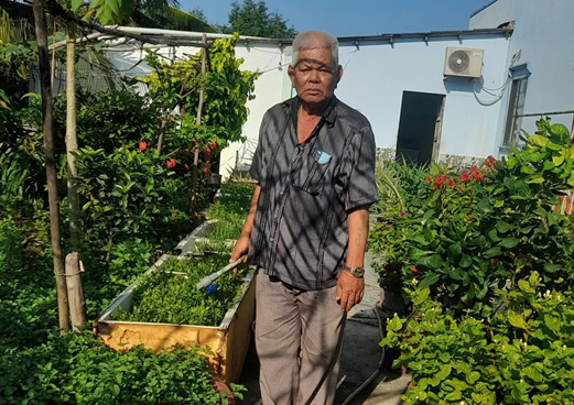 Ông Nguyễn Văn Bôn chăm sóc vườn cây của gia đình.