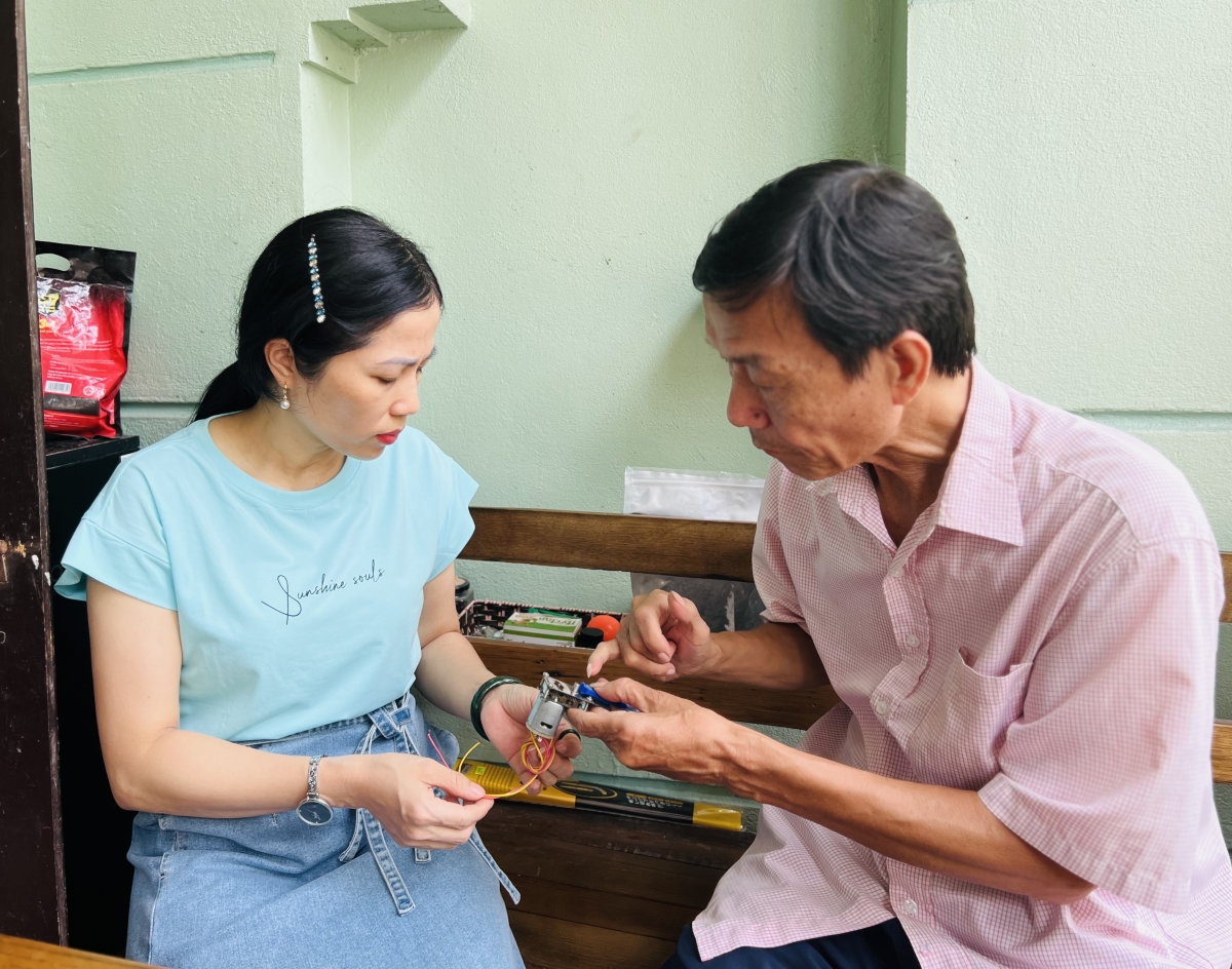 Nghệ nhân Vũ Thanh Luân đang giới thiệu với PV tạp chí Người cao tuổi về cơ chế hoạt động của thiết bị chế bản in mẫu thêu do ông sáng chế