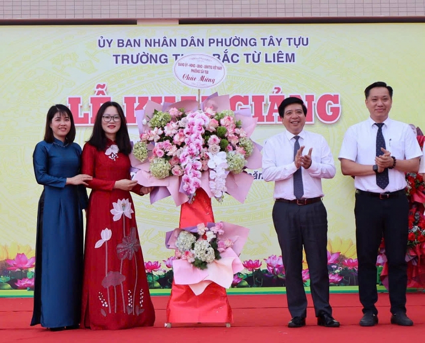 Ông Nguyễn Hữu Tuyên – Bí thư Đảng uỷ, Chủ tịch HĐND phường Tây Tựu (đứng thứ 2, bên phải) tặng hoa chúc mừng nhà trường.