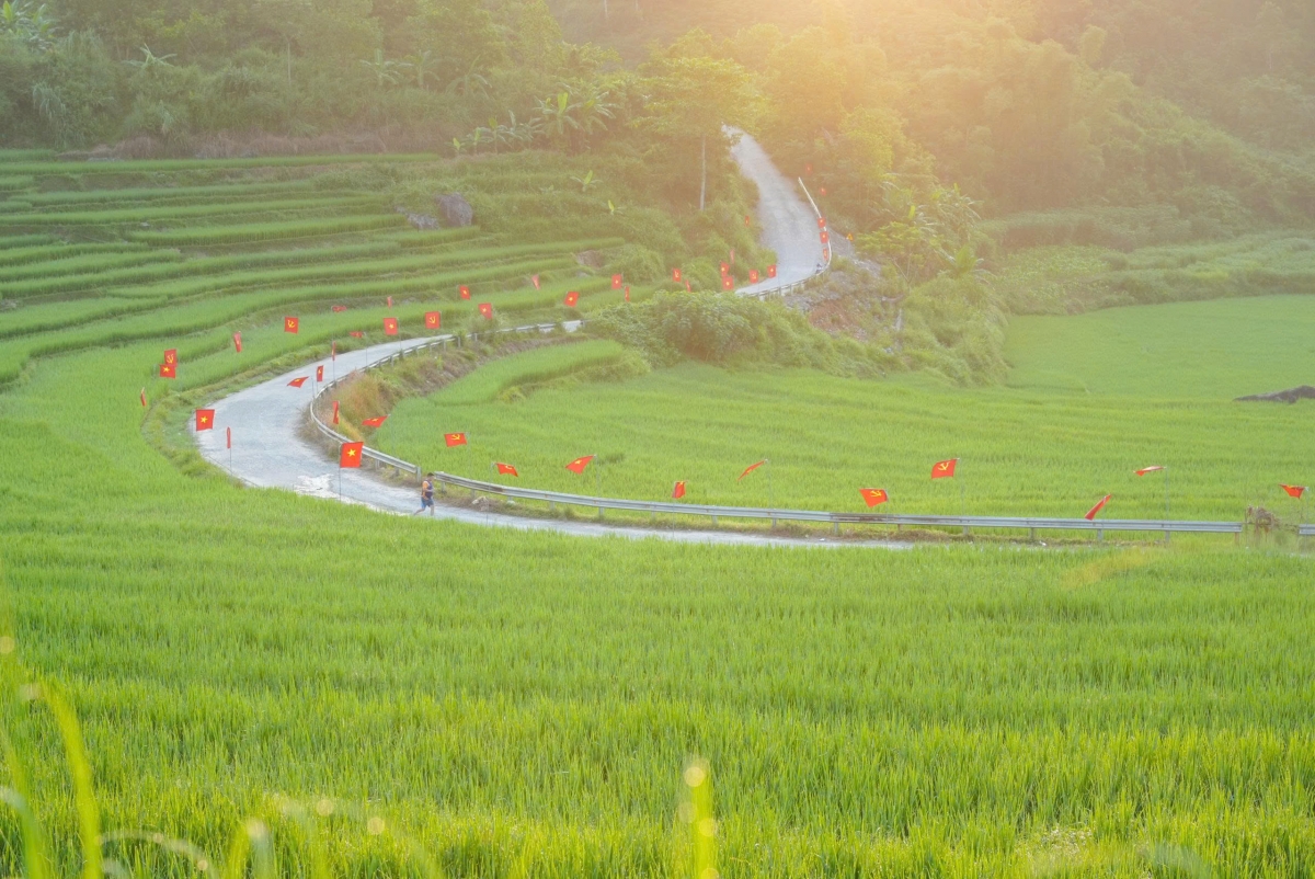Con đường uốn lượn giữa ruộng bậc thang Pù Luông rực rỡ cờ đỏ sao vàng, dẫn du khách đến thôn Đôn – nơi diễn ra triển lãm cộng đồng “Man Kháu – Rice Up”.