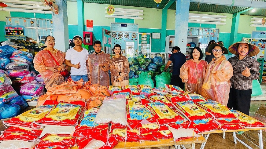 Nhà báo Hà Thị Thu Thuỷ (ngoài cùng bên trái) cùng đoàn thiện nguyện trao quà cho các hộ dân bị ảnh hưởng nặng nề sau trận lũ quét do vỡ hồ chứa nước tại khu vực bờ tràn Tân Lai 