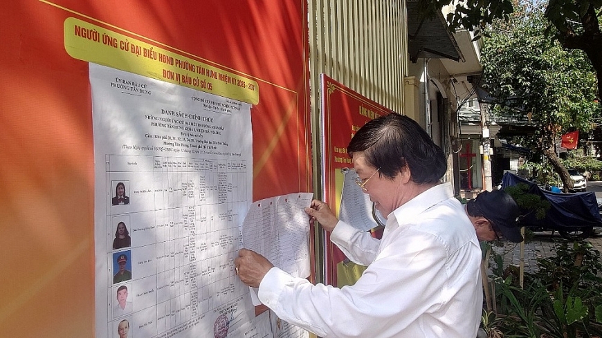 Ông Nguyễn Văn Trường, Trưởng Ban Công tác Mặt trận khu phố 33, thành viên Tổ bầu cử khu vực bỏ phiếu số 18, dán danh sách các ứng cử viên