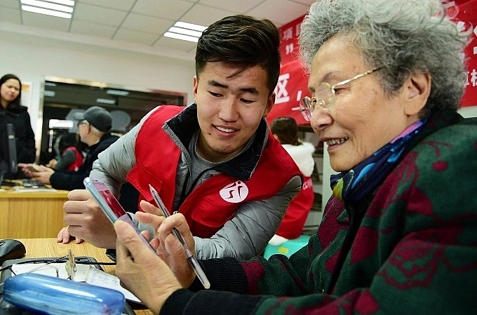 Một tình nguyện viên hướng dẫn một phụ nữ cao tuổi cách sử dụng smartphone ở tỉnh Giang Tô. Ảnh:AFP