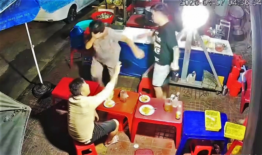 Cụ bà phục vụ trong quán ăn khuya ôm mặt khóc sau khi bị nam thanh niên dùng tay đánh vào mặt. Ảnh cắt từ clip.