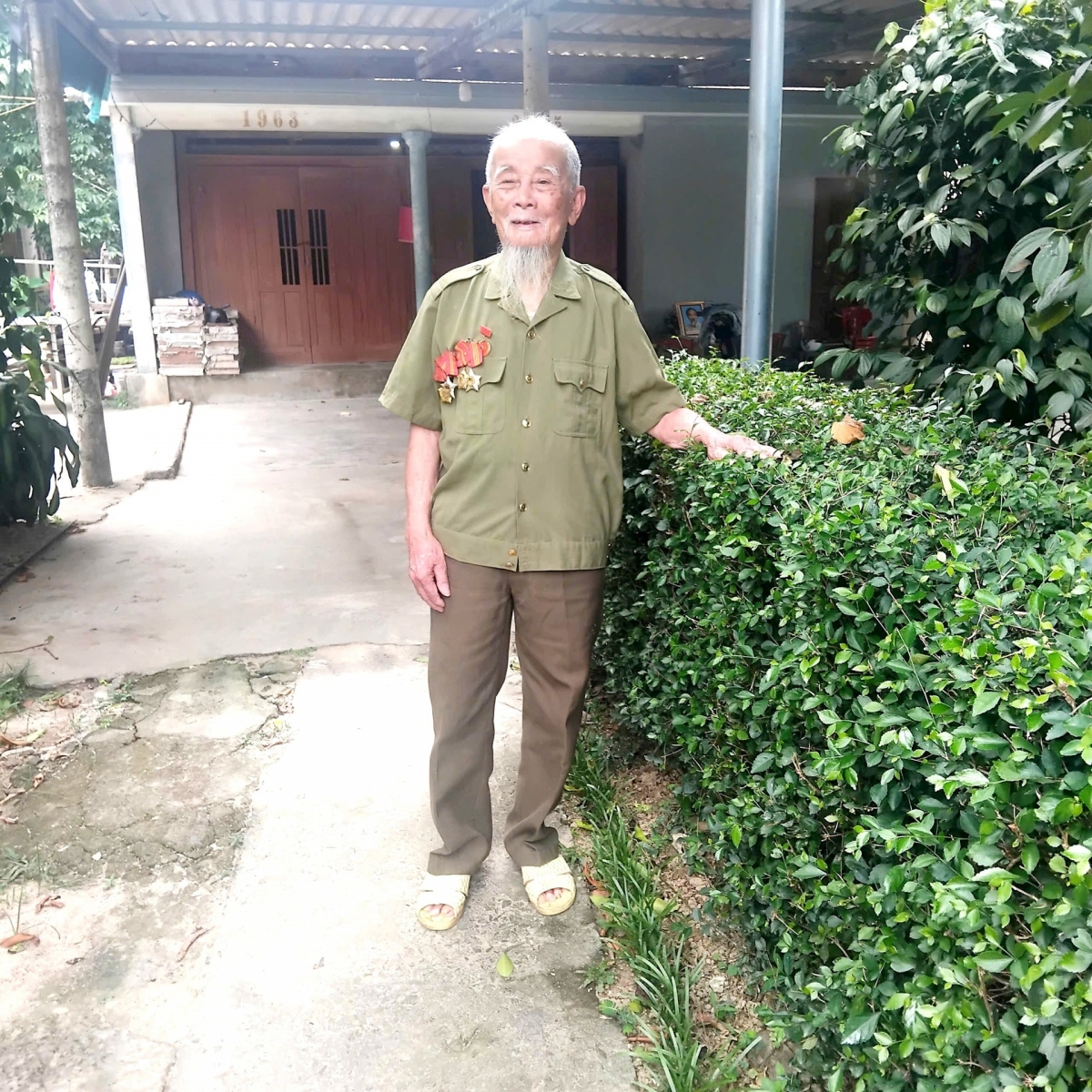 Cụ Phan Văn Thi bên căn nhà của mình tại quê hương