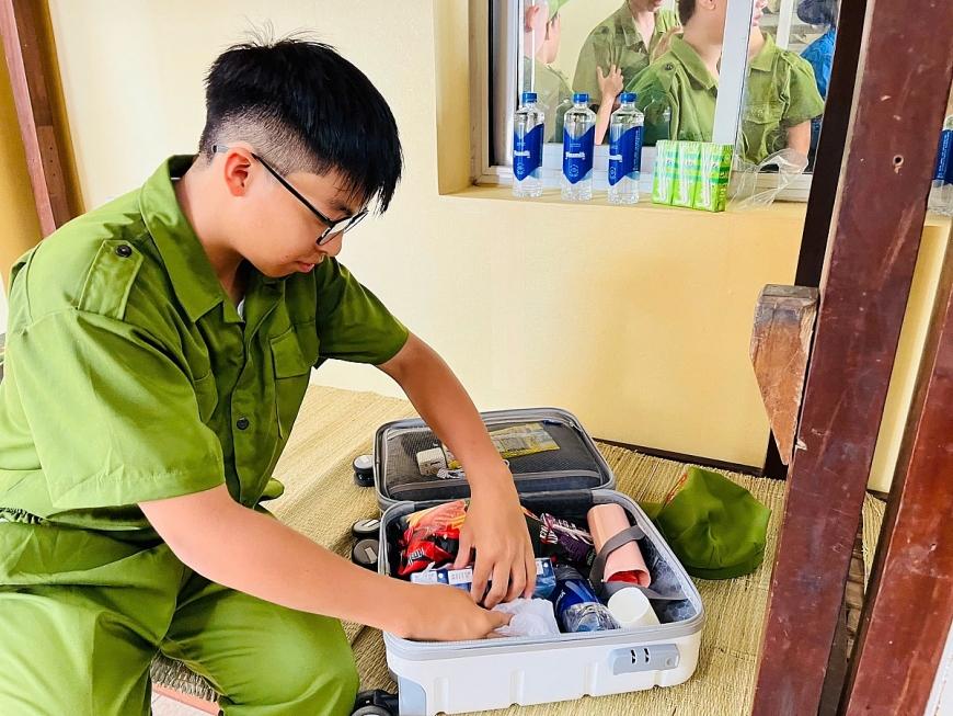 Phúc Khang học cách tự xắp xếp đồ dùng trong ngày đầu tham gia “Học làm chiến sĩ công an” (Ảnh: VN). 