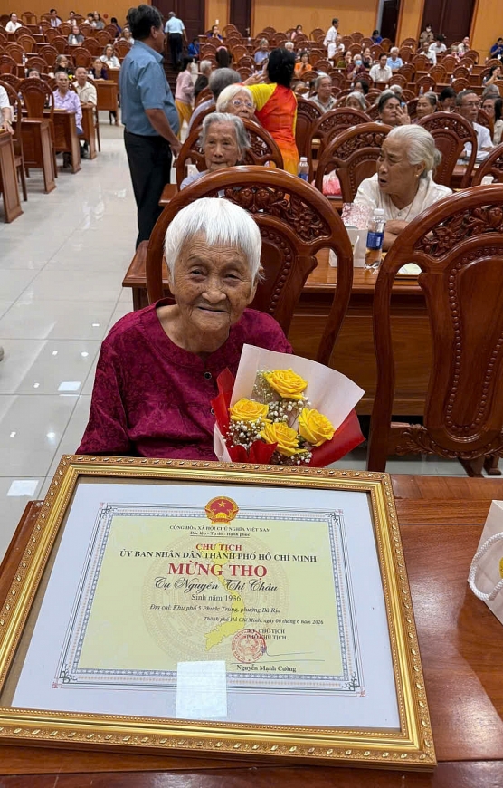 Cụ Nguyễn Thị Châu, sinh năm 1936 vui mừng nhận Giấy mừng thọ và hoa chúc mừng tại lễ chúc thọ, mừng thọ người cao tuổi năm 2026