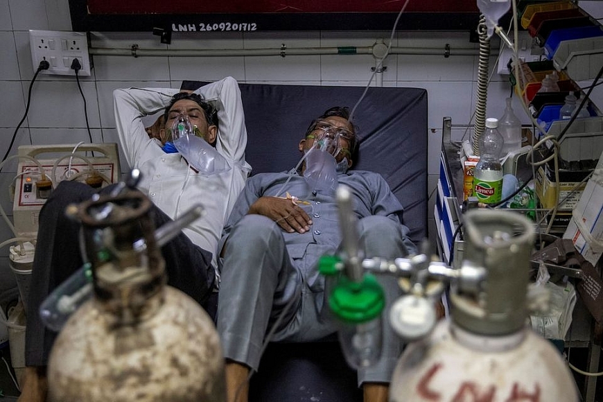 Hai bệnh nhân COVID-19 nằm chung một chiếc giường tại một bệnh viện ở New Delhi, Ấn Độ. Ảnh: Reuters