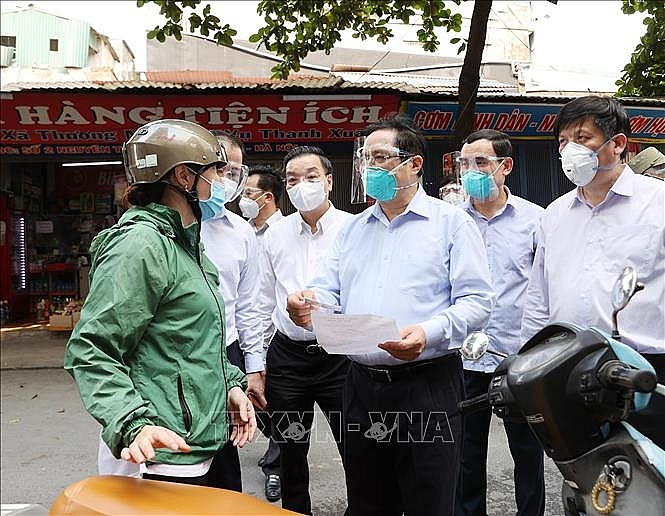 Thủ tướng Phạm Minh Chính kiểm tra giấy phép đi đường và khai báo y tế của người dân trên địa bàn quận Thanh Xuân. Ảnh: Dương Giang/TTXVN