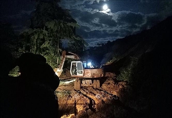 Lực lượng chức năng tích cực thông tuyến đường dẫn vào khu vực sạt lở. Ảnh: TTXVN