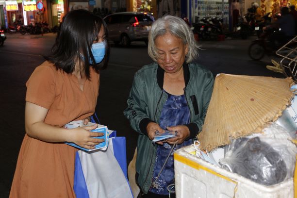 C&aacute;c bạn t&igrave;nh nguyện trao tặng khẩu trang y tế cho một người lang thang tr&ecirc;n đường Phan Đăng Lưu