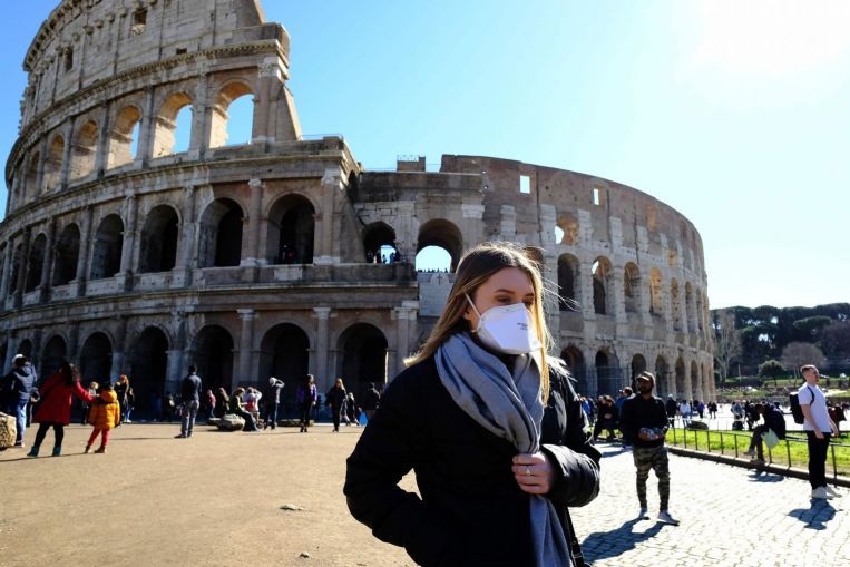 Một du kh&aacute;ch đeo khẩu trang thi thăm quan điểm du lịch tại Italia. (Ảnh AFP)