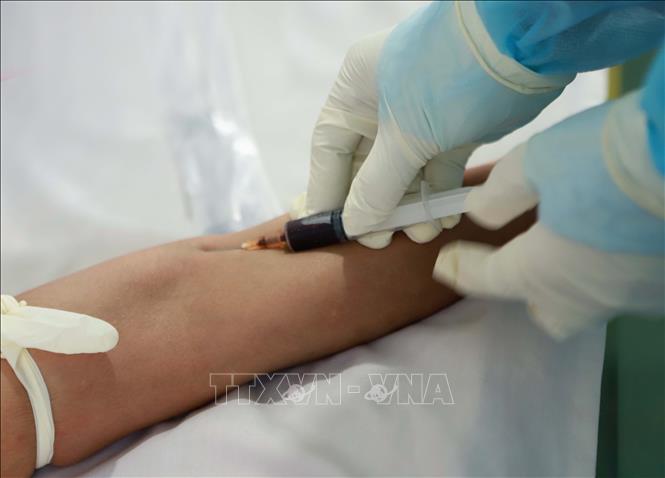Kĩ thuật vi&ecirc;n lấy mẫu m&aacute;u bệnh nh&acirc;n l&agrave;m x&eacute;t nghiệm. Ảnh: Ho&agrave;ng H&ugrave;ng/TTXVN