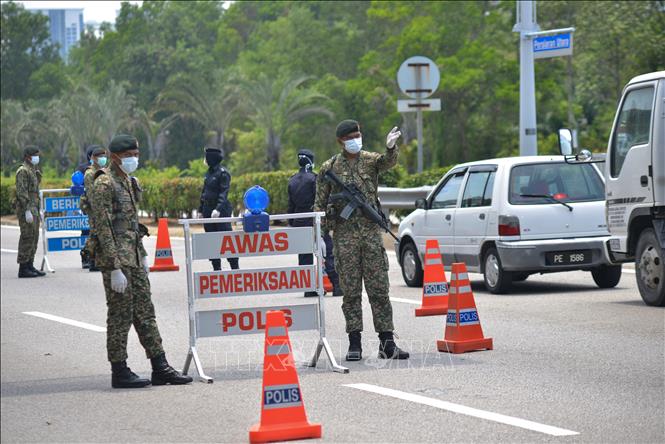 Binh sĩ Malaysia l&agrave;m nhiệm vụ tại một chốt chặn trong thời gian thực thi lệnh phong tỏa nhằm ngăn dịch COVID-19 l&acirc;y lan, ở Putrajaya ng&agrave;y 22/3/2020. Ảnh: THX/TTXVN