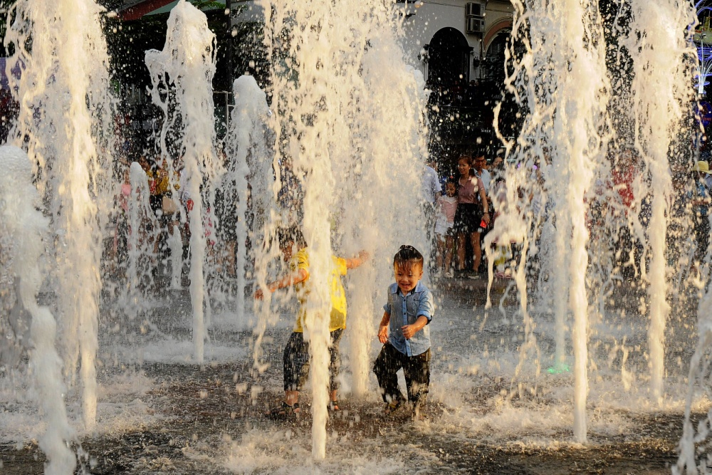 Sự hồn nhi&ecirc;n, trong trẻo của em b&eacute; v&ocirc; tư n&ocirc; đ&ugrave;a với những v&ograve;i phun nước tr&ecirc;n phố đi bộ Nguyễn Huệ