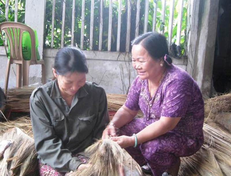 B&agrave; Huệ (b&ecirc;n phải) hướng dẫn chị em l&agrave;m chổi đ&oacute;t