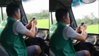 Tài xế dùng khuỷu tay lái xe, tay bấm điện thoại 
