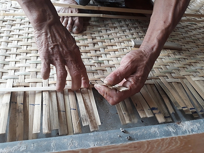 Người thợ tỉ mỉ đan từng nan tre cho thật đều và chặt