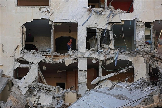 Một người Palestine kiểm tra tòa nhà bị phá hủy sau trận không kích của Israel.