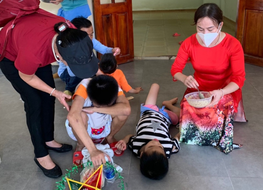 : Bà Phạm Hậu (phải) tặng quà và cho trẻ ăn tại Làng Hòa Bình, xã Tam Đàn (Phú Ninh, Quảng Nam) năm 2021